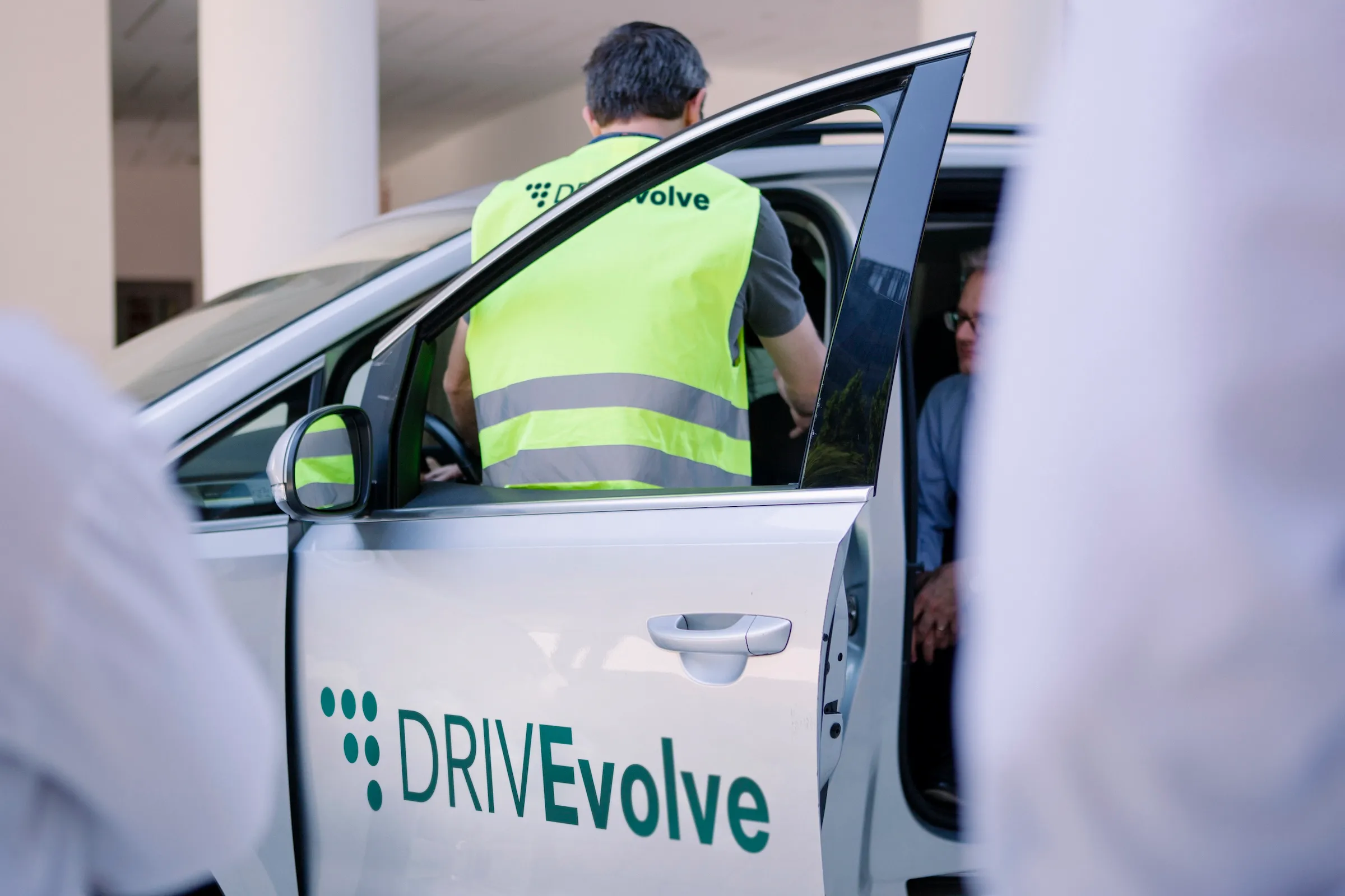 persone che osservano un istruttore del corso di guida ecodrive italia di DRIVEvolve mentre sale in auto