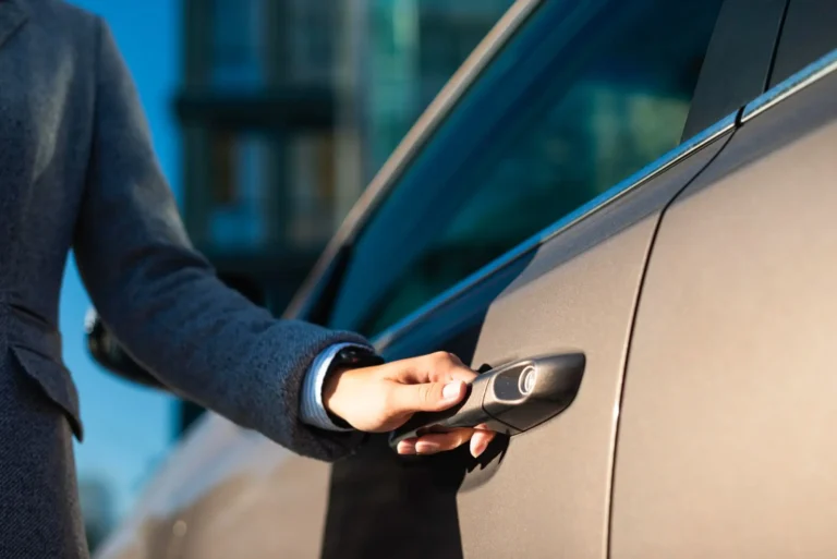 come funziona l'auto aziendale: primo piano di mano di donna che apre la portiera di un auto grigia