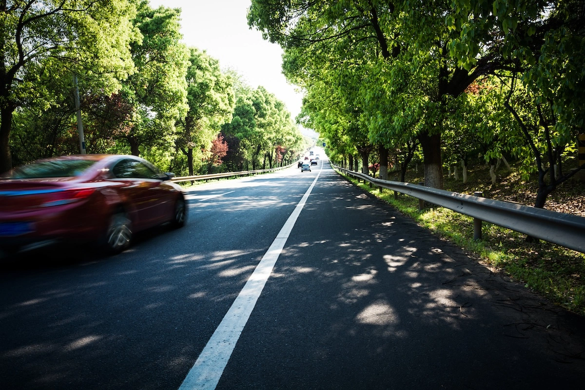 auto aziendale rossa su una strada alberata