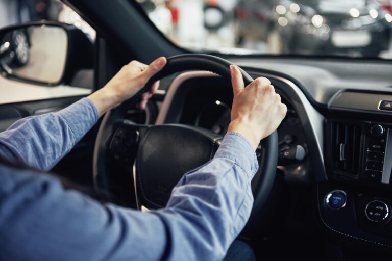 primo piano di mani sul volante dell'auto
